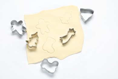 Photo of Raw dough and cookie cutters on white background, above view