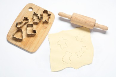 Raw dough, cookie cutters, board and rolling pin on white background, above view