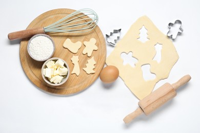 Photo of Raw dough, cookie cutters, whisk, ingredients and rolling pin on white background, flat lay