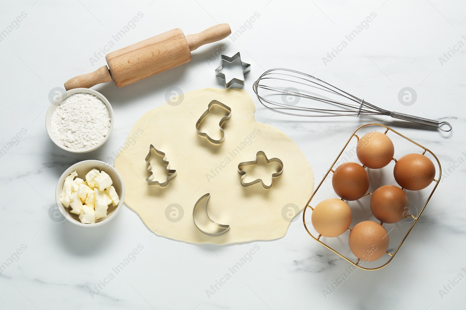 Photo of Flat lay composition with raw dough, cookie cutters and ingredients on white marble table