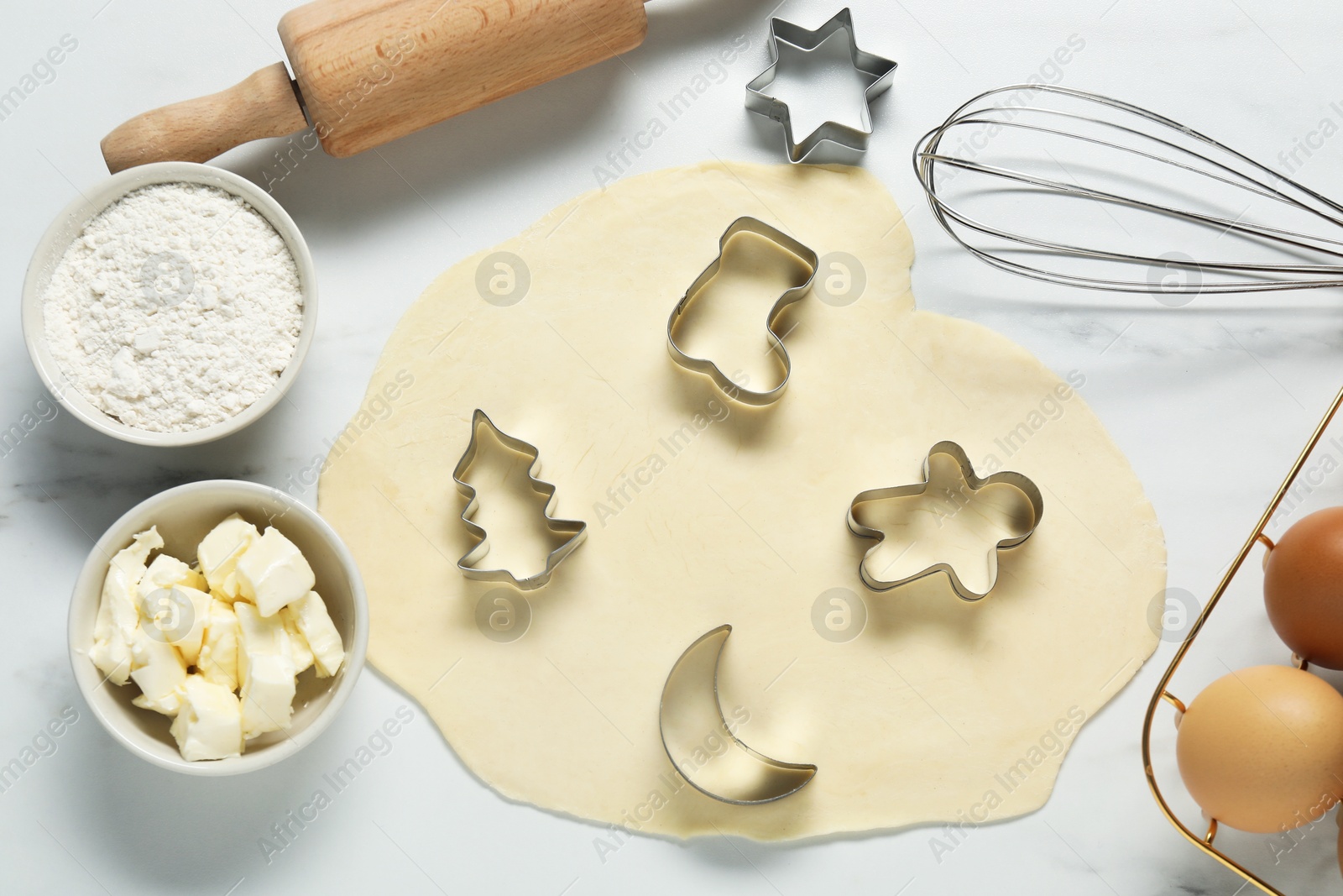 Photo of Flat lay composition with raw dough, cookie cutters and ingredients on white marble table