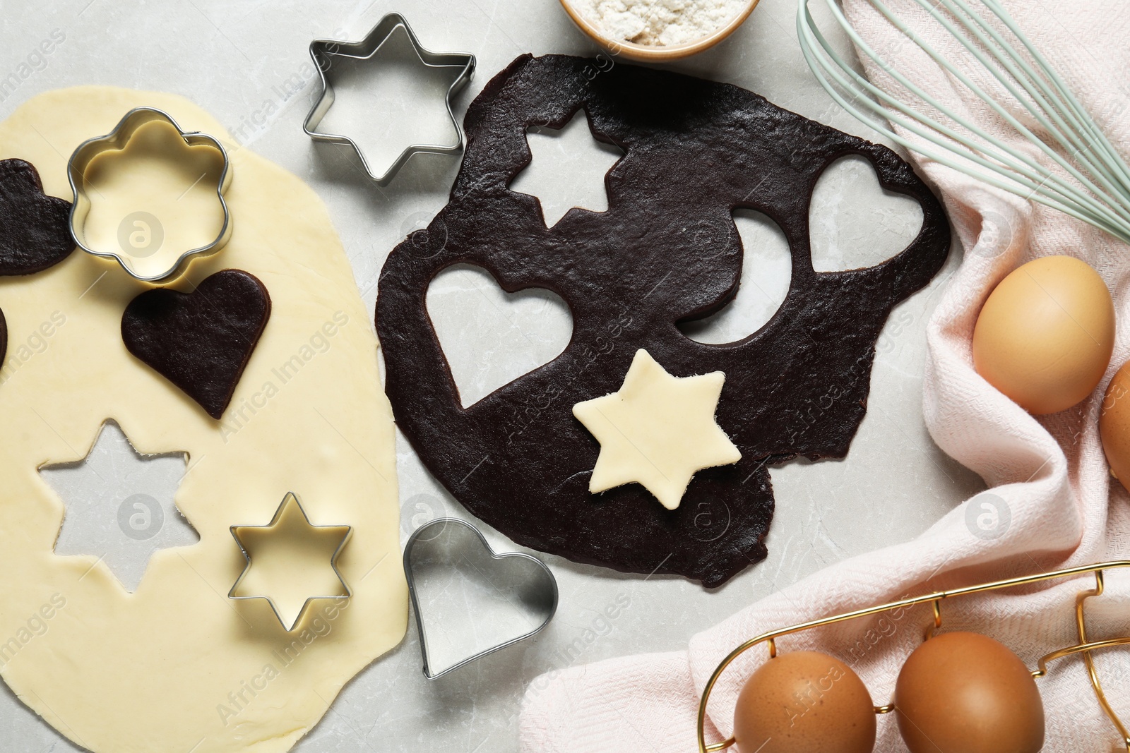 Photo of Raw doughs and cookie cutters on light table, flat lay