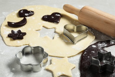 Photo of Raw doughs, rolling pin and cookie cutters on light table, closeup