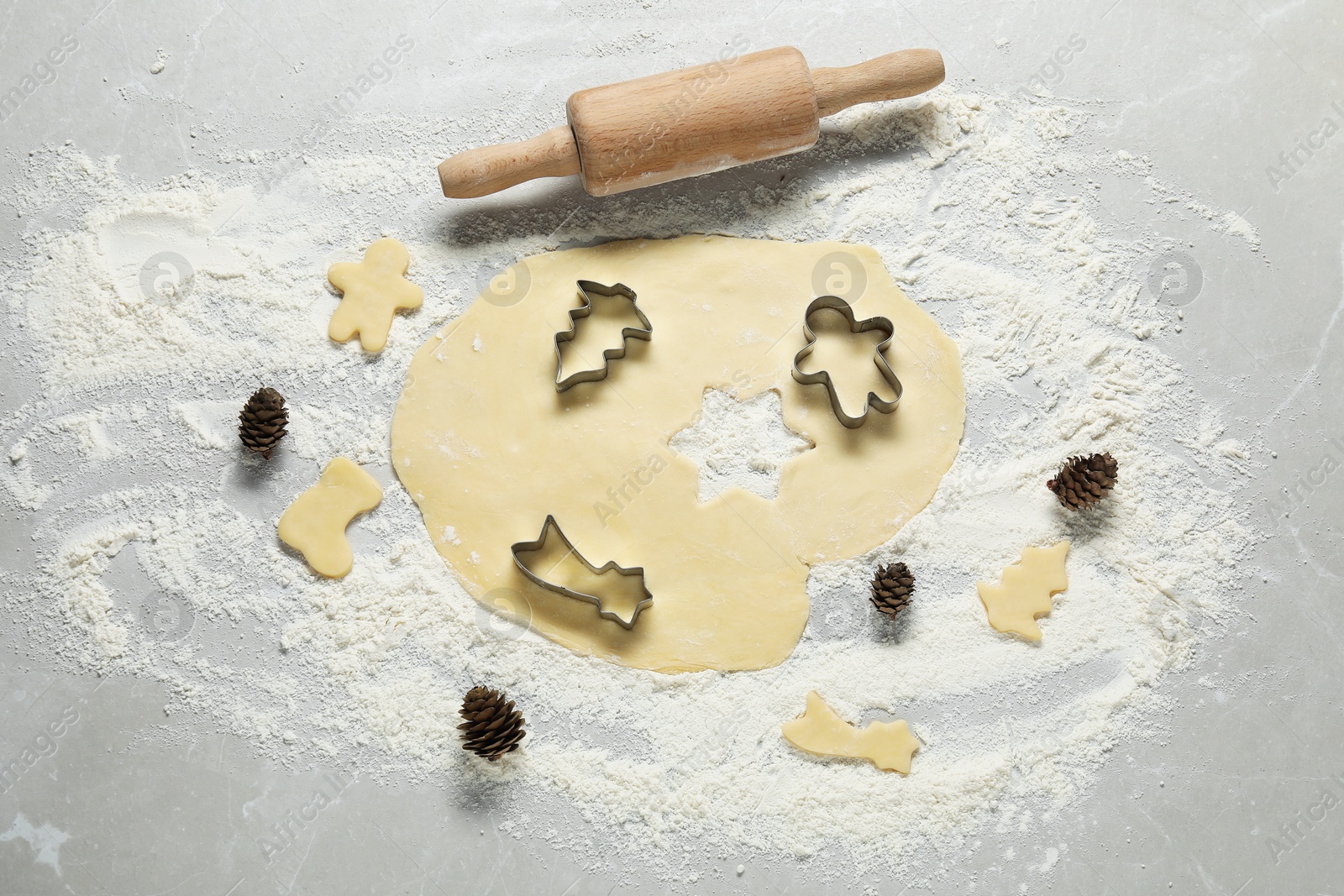 Photo of Raw dough, rolling pin and cookie cutters on light table, flat lay