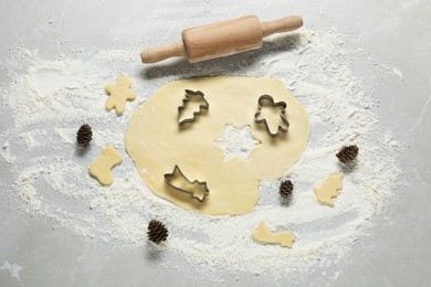 Photo of Raw dough, rolling pin and cookie cutters on light table, flat lay