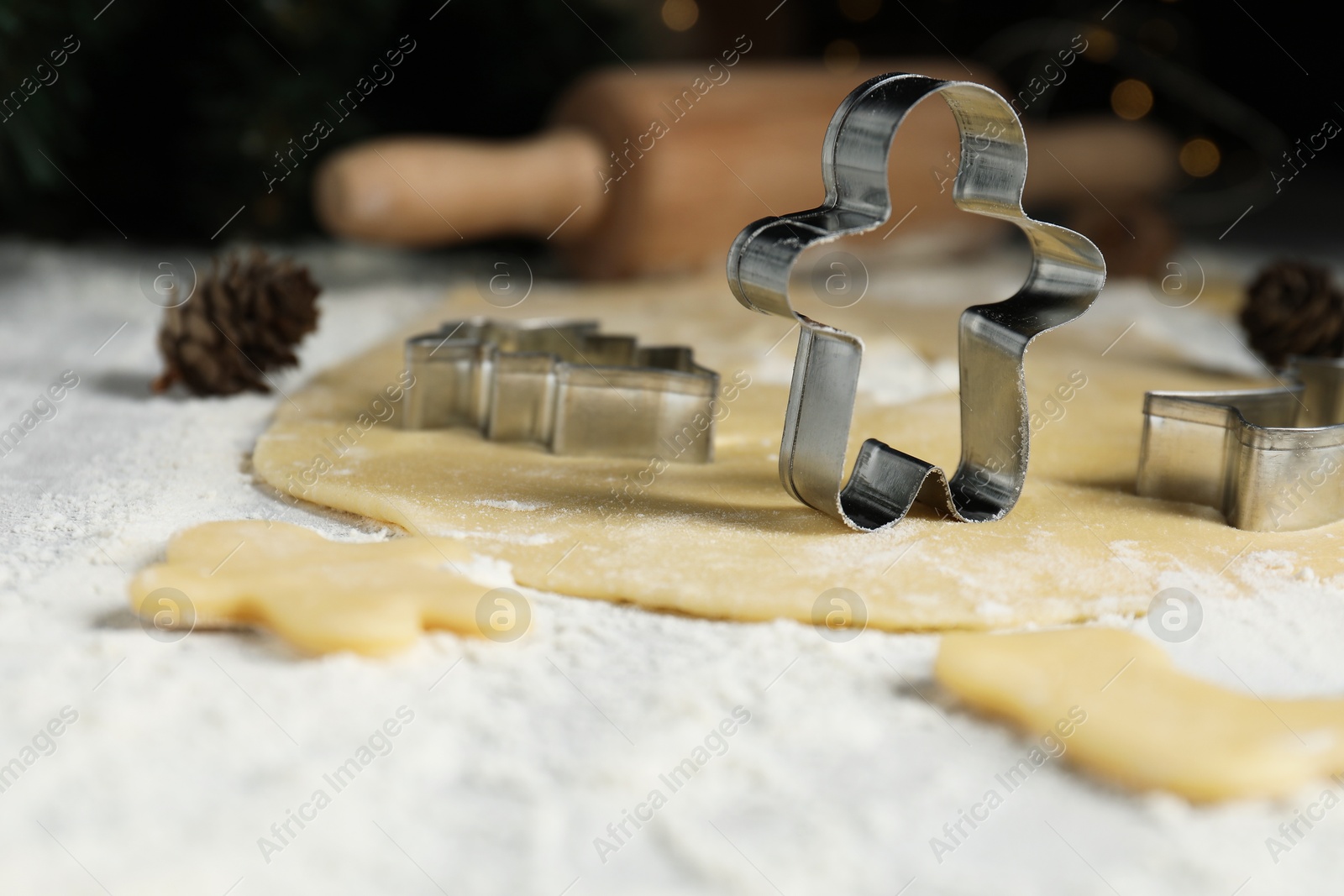 Photo of Raw dough, cookie cutters and flour on table, closeup