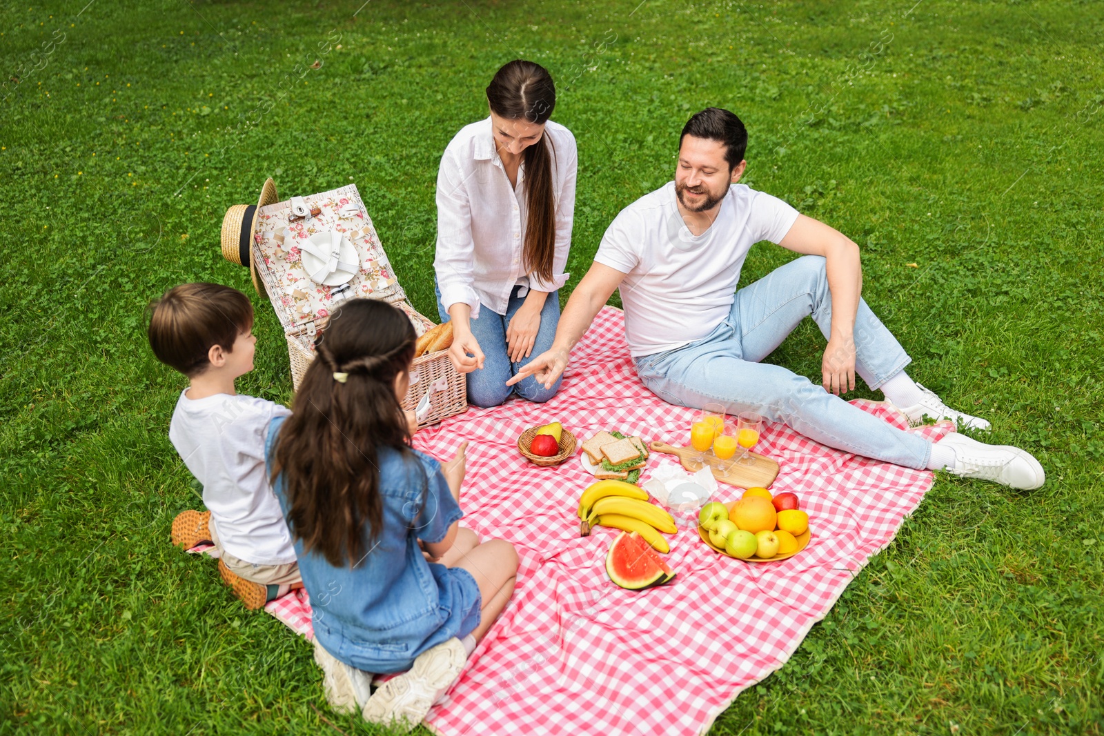 Photo of Happy family playing rock, paper and scissors during picnic in park