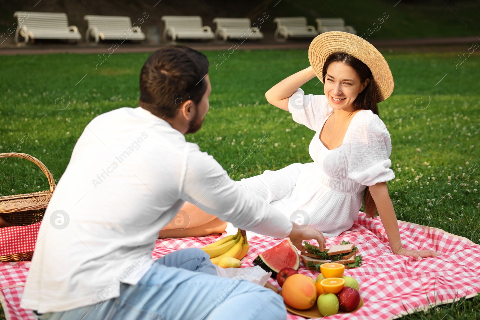 Photo of Lovely couple having picnic on green grass outdoors