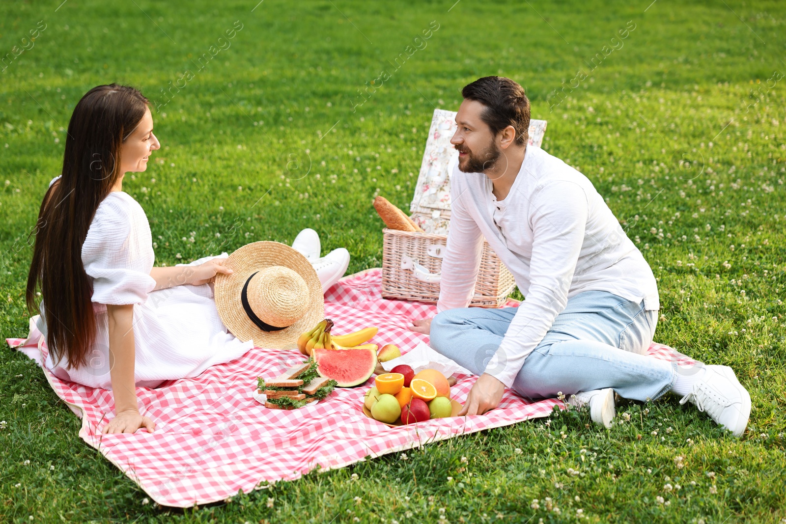 Photo of Lovely couple having picnic on green grass outdoors