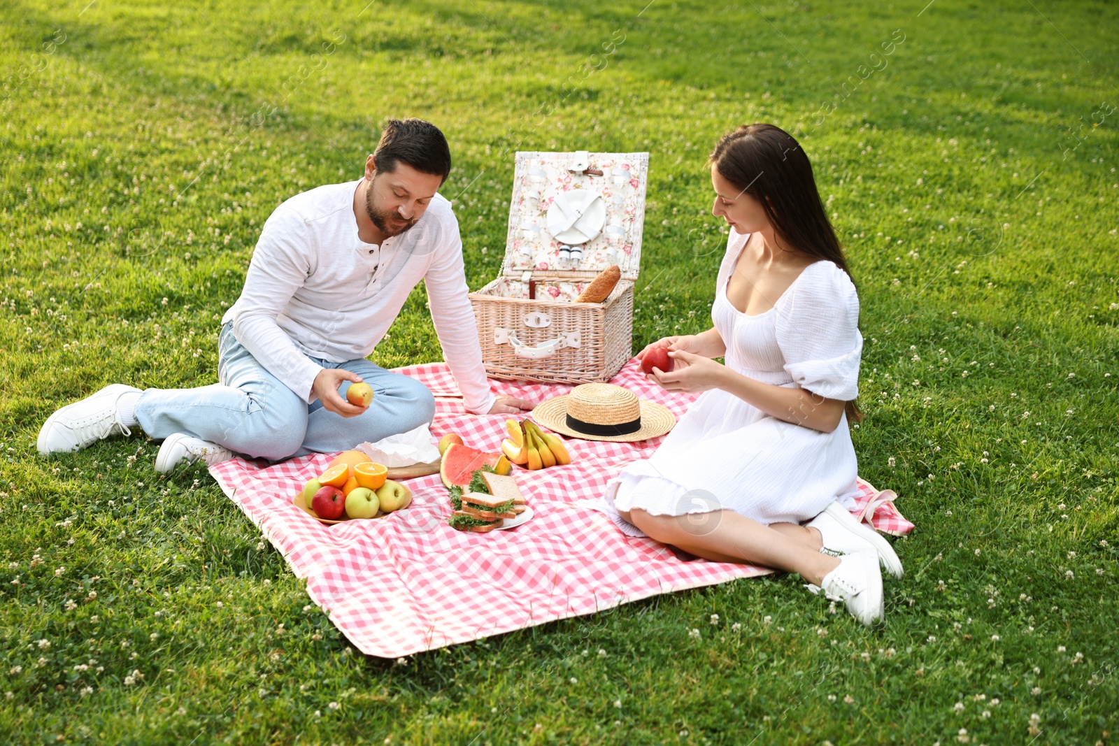 Photo of Lovely couple having picnic on green grass outdoors