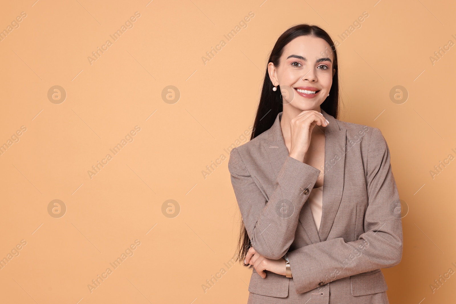 Photo of Beautiful woman in stylish jacket on pale orange background, space for text