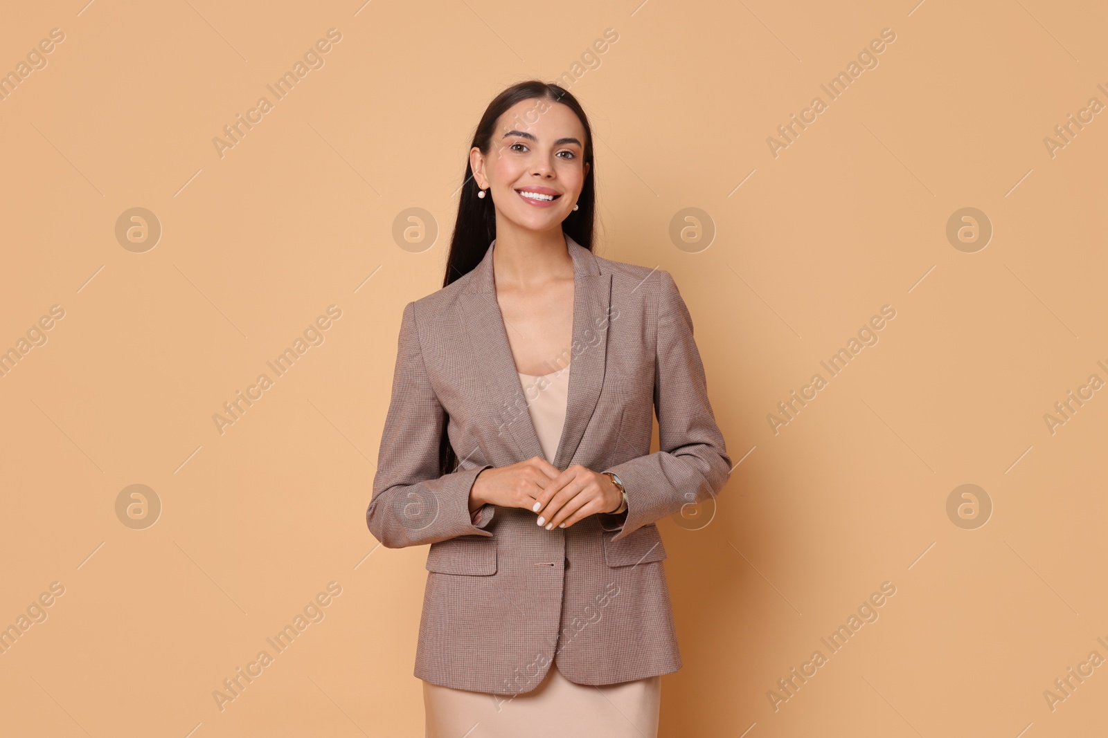 Photo of Beautiful woman in stylish jacket and beige dress on pale orange background