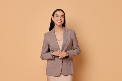 Beautiful woman in stylish jacket and beige dress on pale orange background