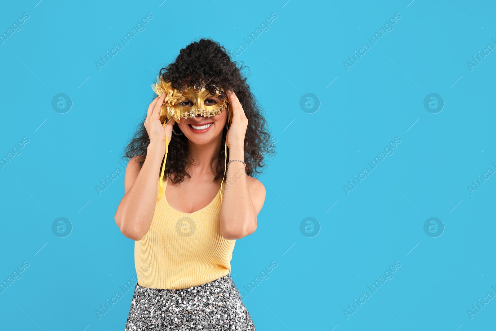 Photo of Happy young woman with carnival mask on light blue background, space for text