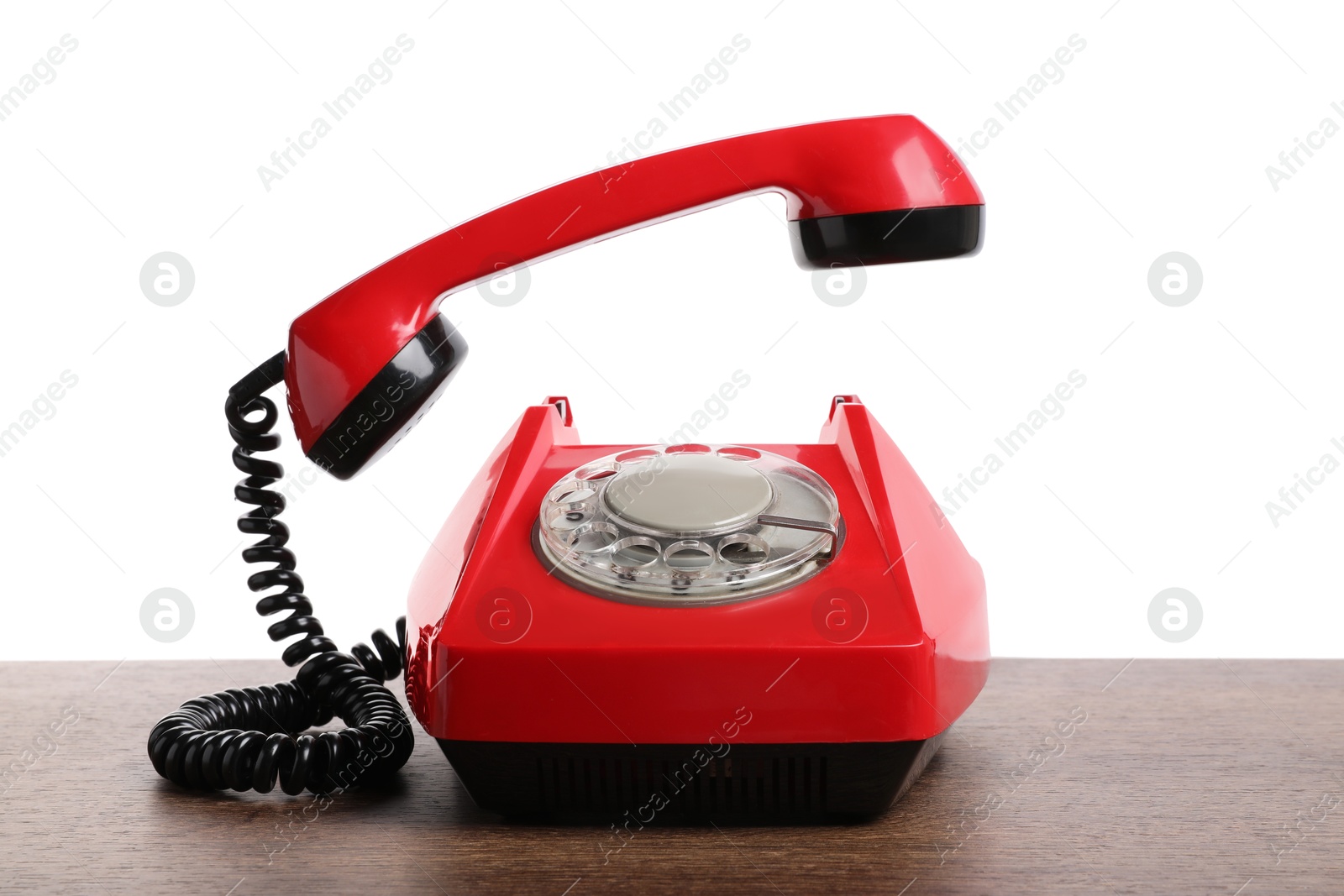 Photo of One red telephone with handset on wooden table against white background