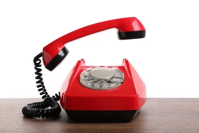 Photo of One red telephone with handset on wooden table against white background