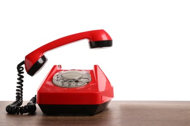 Photo of One red telephone with handset on wooden table against white background