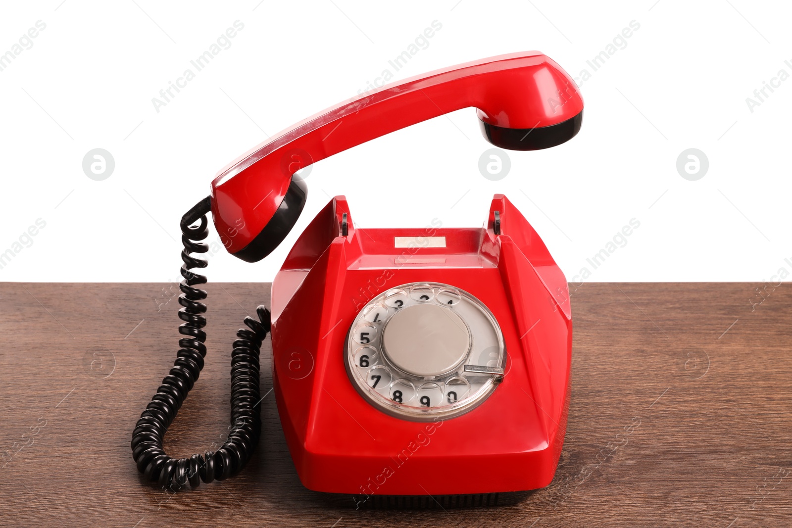 Photo of One red telephone with handset on wooden table against white background