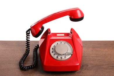 One red telephone with handset on wooden table against white background