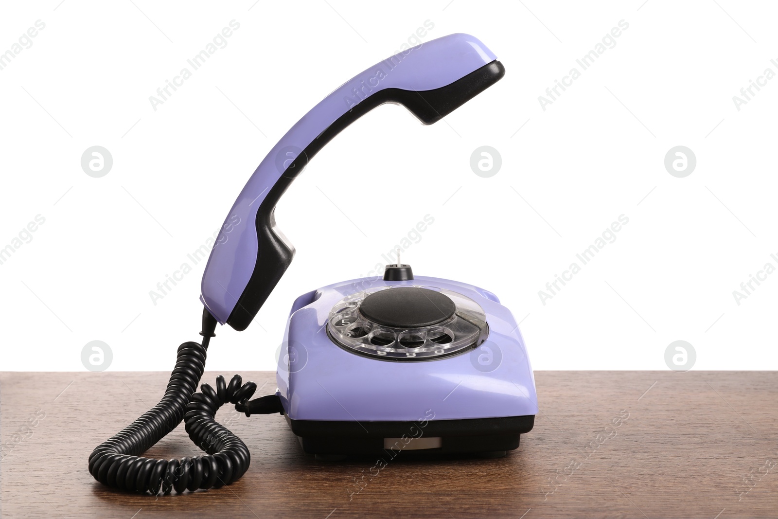 Photo of One violet telephone with handset on wooden table against white background