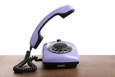 Photo of One violet telephone with handset on wooden table against white background