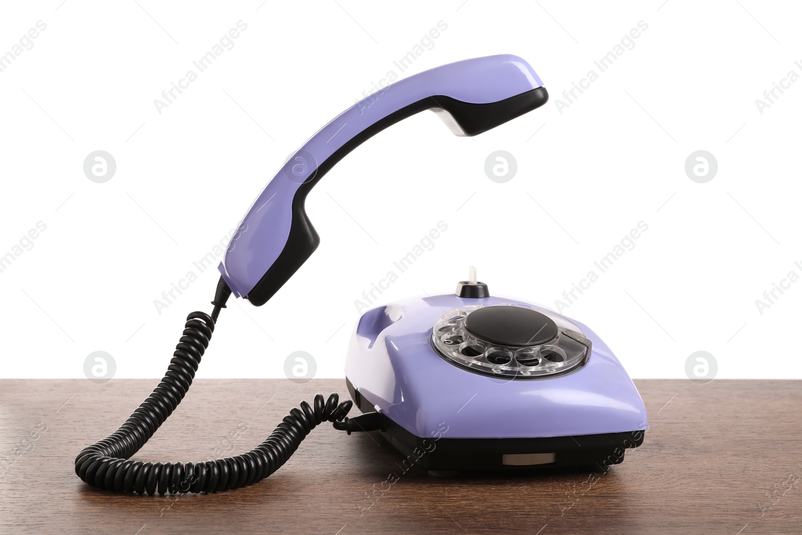 Photo of One violet telephone with handset on wooden table against white background