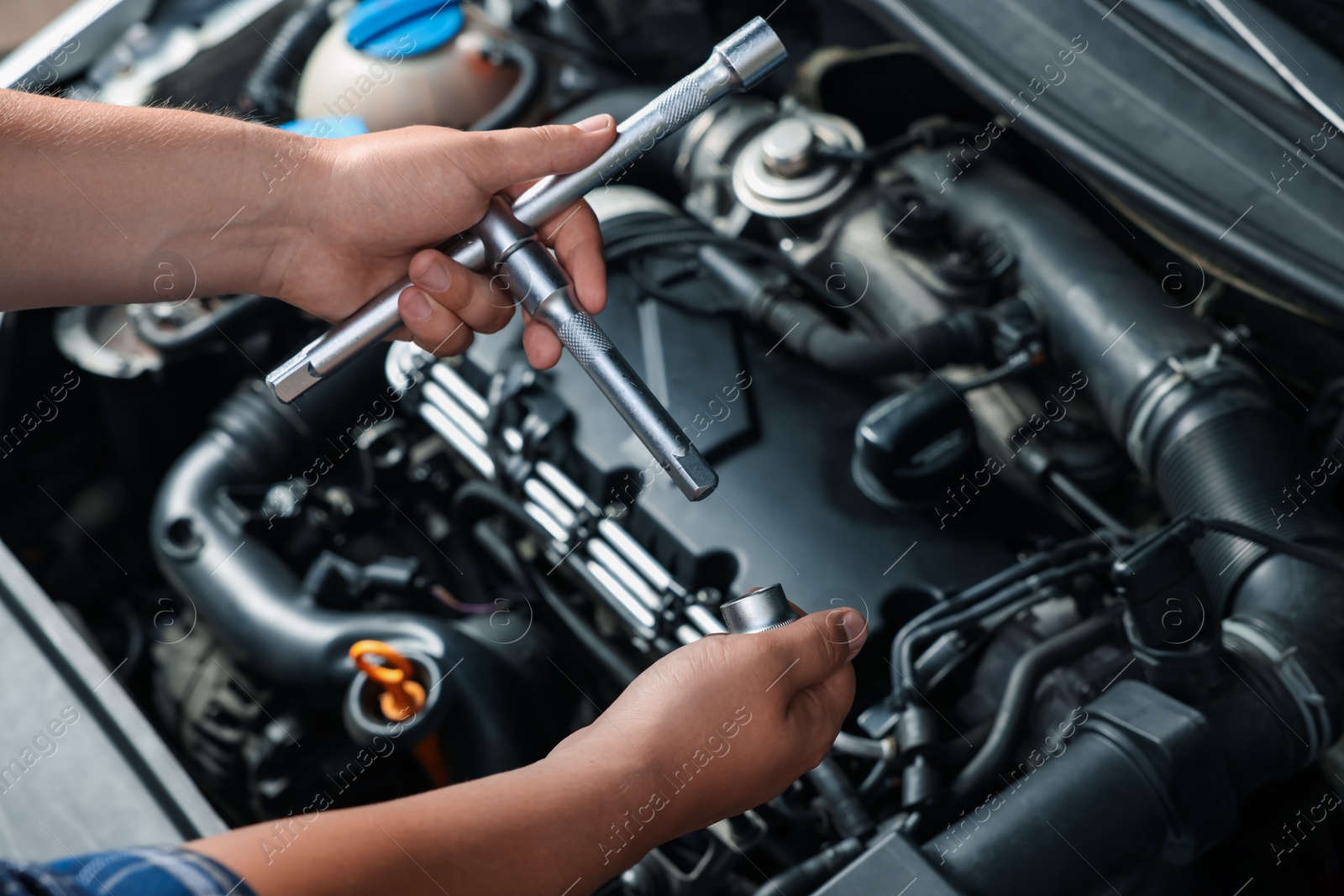 Photo of Auto mechanic with different tools fixing car at automobile repair shop, closeup