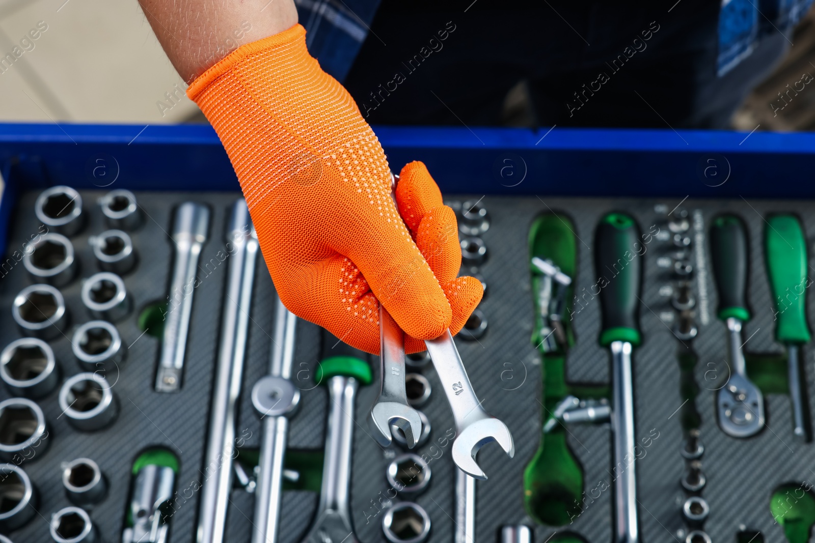 Photo of Auto mechanic with ratcheting wrenches at automobile repair shop, closeup