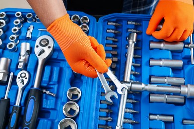 Auto mechanic with ratcheting wrenches at automobile repair shop, closeup