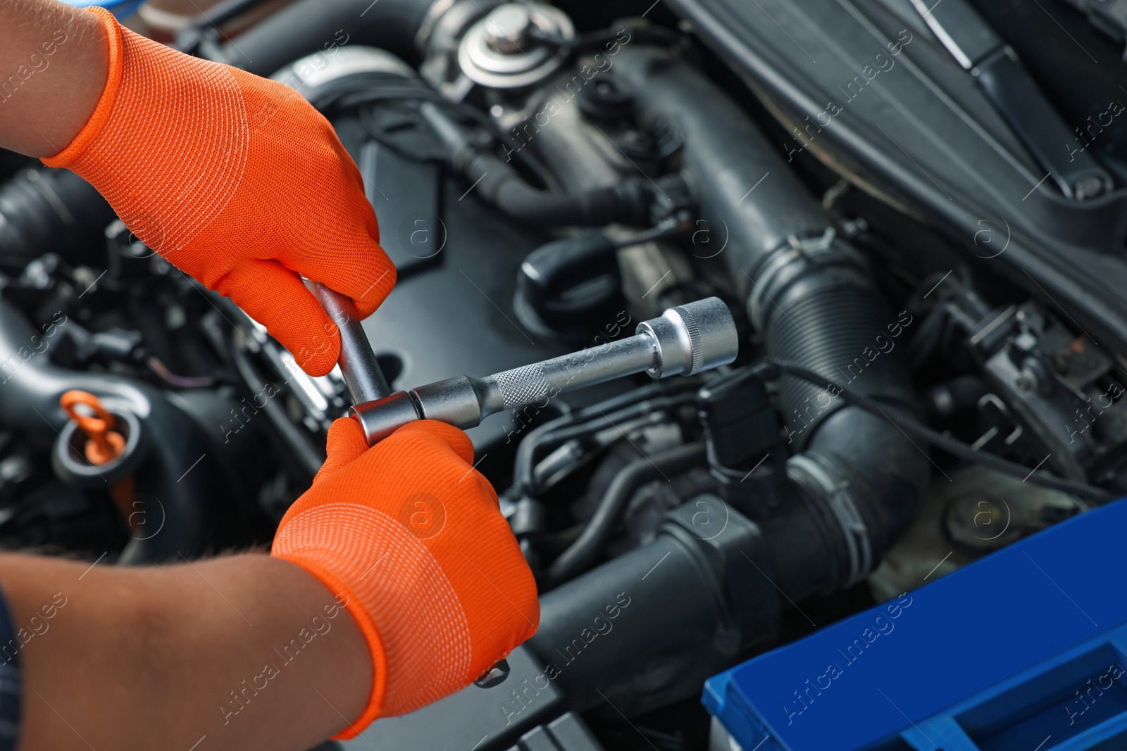 Photo of Auto mechanic with different tools fixing car at automobile repair shop, closeup