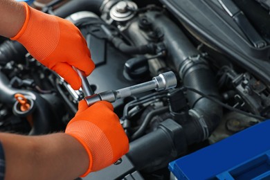 Photo of Auto mechanic with different tools fixing car at automobile repair shop, closeup