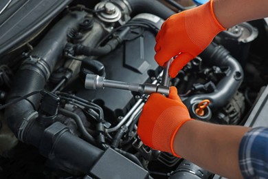 Auto mechanic with different tools fixing car at automobile repair shop, closeup