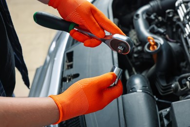 Auto mechanic with torque wrench fixing car at automobile repair shop, closeup