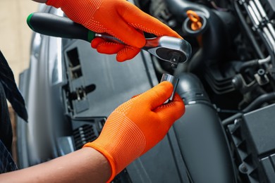 Photo of Auto mechanic with torque wrench fixing car at automobile repair shop, closeup