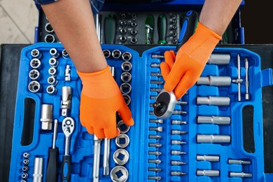 Auto mechanic with torque wrench and different tools at automobile repair shop, top view