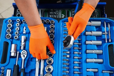 Photo of Auto mechanic with torque wrench and different tools at automobile repair shop, top view