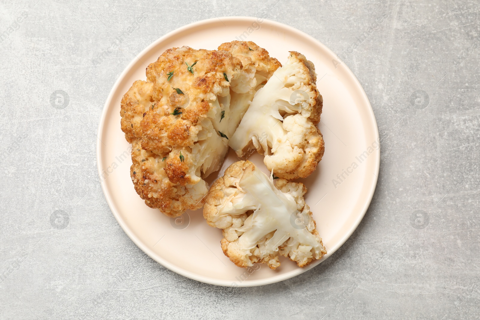 Photo of Delicious baked cauliflower on gray textured table, top view