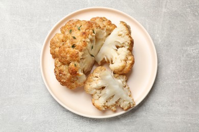 Delicious baked cauliflower on gray textured table, top view