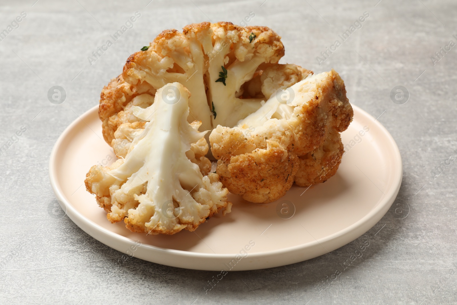 Photo of Delicious baked cauliflower on gray textured table, closeup