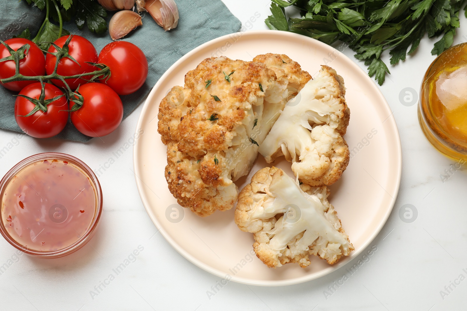 Photo of Delicious baked cauliflower and products on white table, flat lay