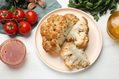 Delicious baked cauliflower and products on white table, flat lay