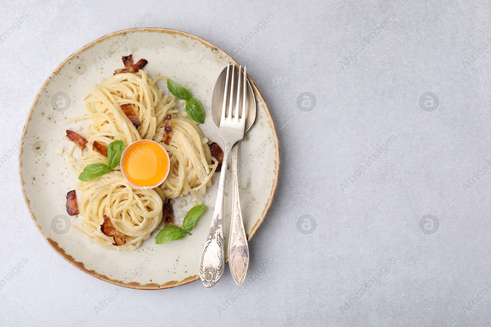 Photo of Delicious pasta Carbonara served on grey table, top view. space for text