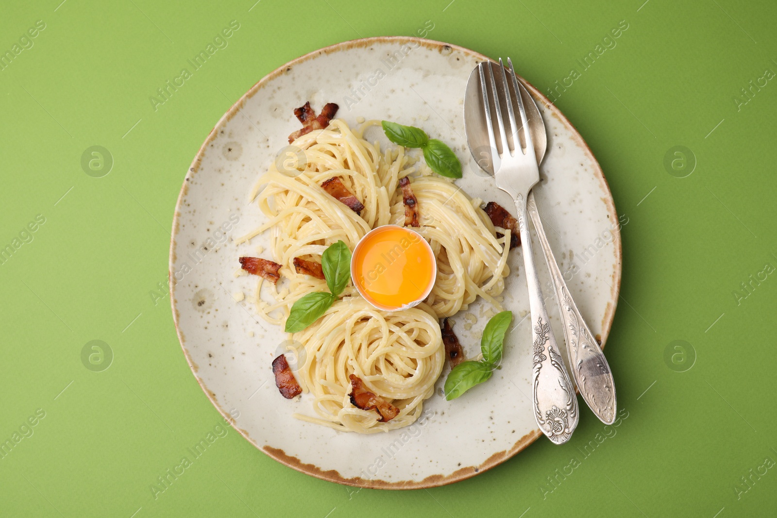 Photo of Delicious pasta Carbonara served on green background, top view