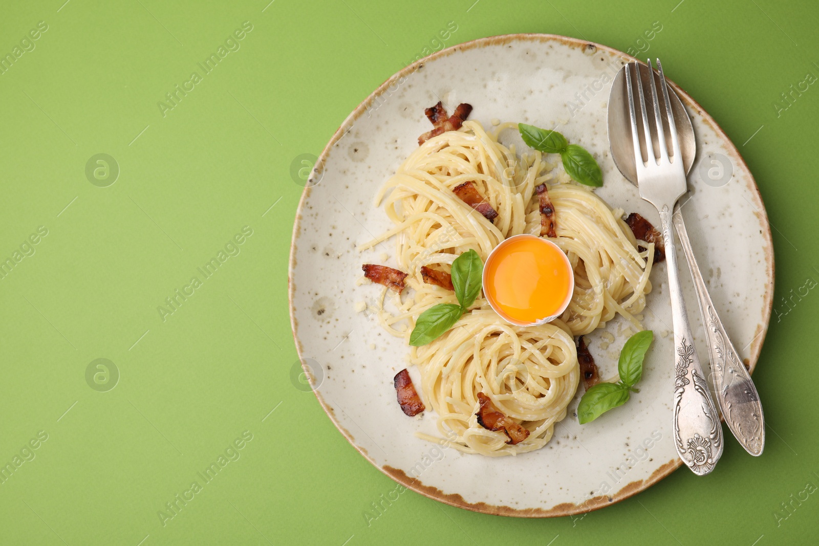 Photo of Delicious pasta Carbonara served on green background, top view. Space for text