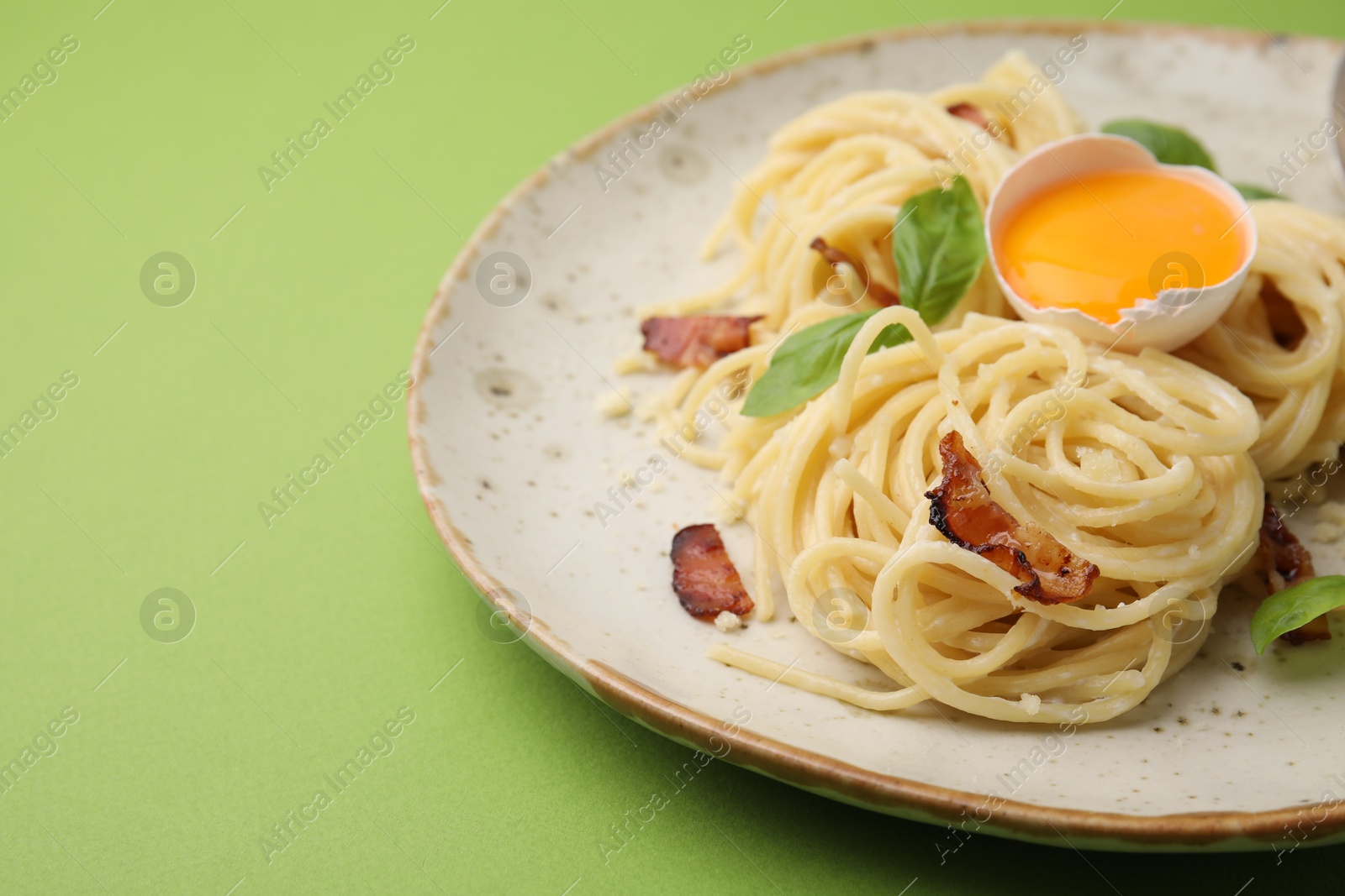 Photo of Delicious pasta Carbonara served on green background, closeup