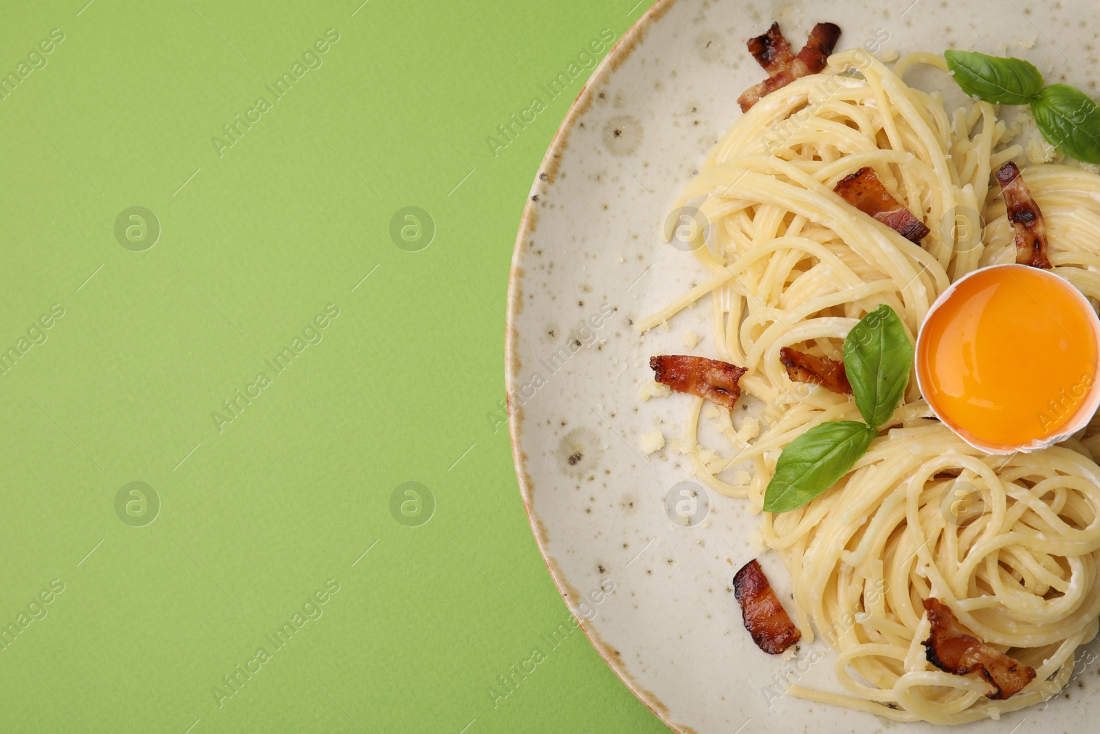 Photo of Delicious pasta Carbonara served on green background, top view. Space for text