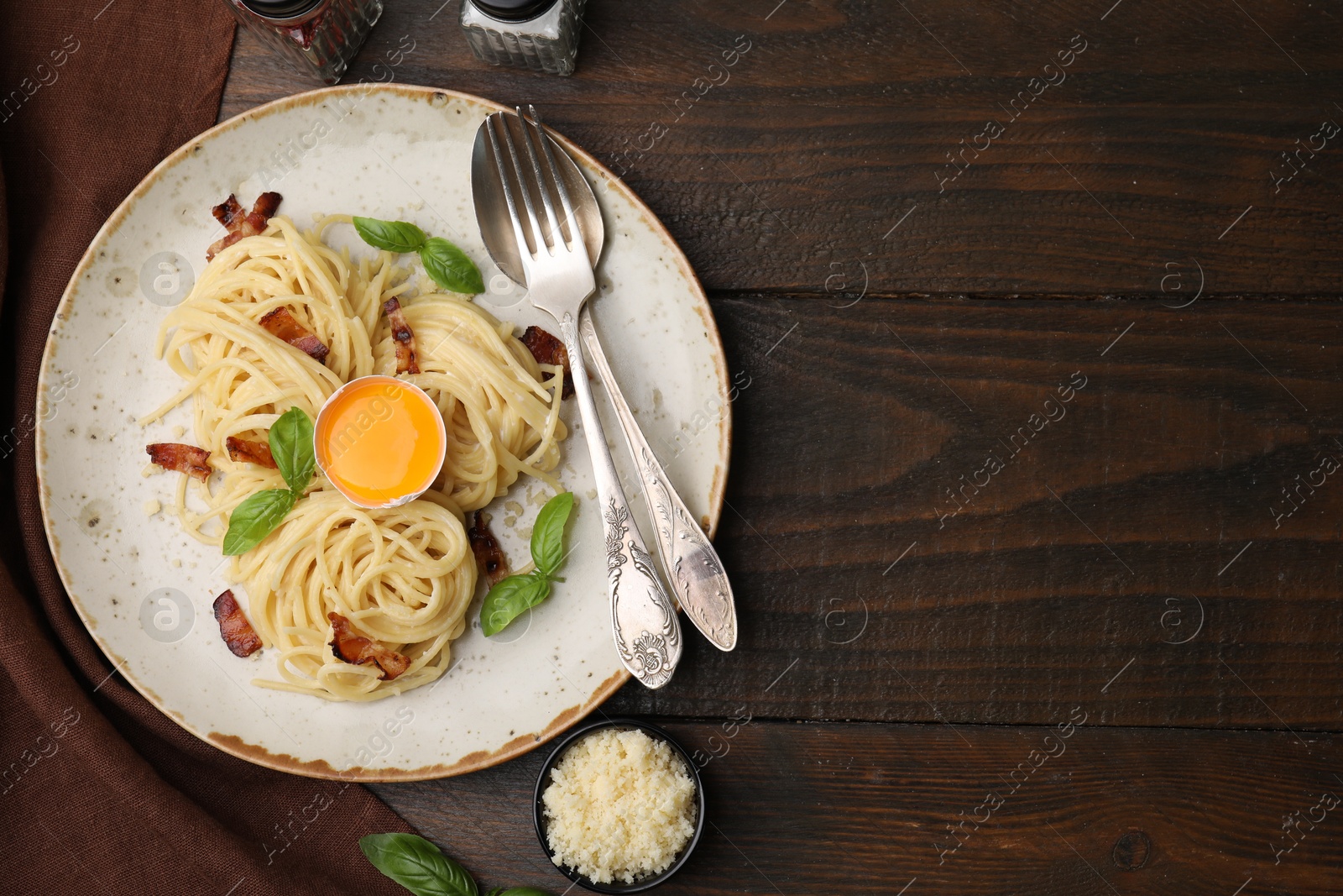 Photo of Delicious pasta Carbonara served on wooden table, top view. Space for text