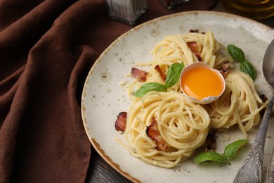 Photo of Delicious pasta Carbonara served on wooden table, closeup