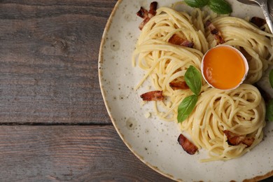 Photo of Delicious pasta Carbonara served on wooden table, top view. Space for text