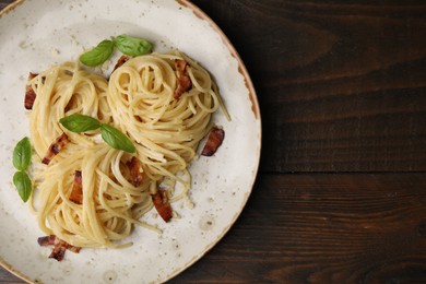 Photo of Delicious pasta with bacon and basil on wooden table, top view. Space for text